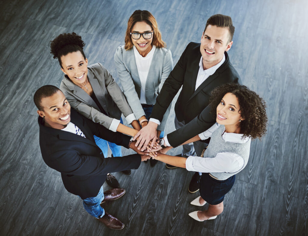 Team van diverse professionals met handen op elkaar, symbool voor samenwerking en inclusiviteit