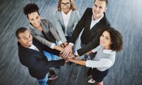 Onze missie en visie – Samen bouwen aan een mensgerichte arbeidsmarkt bij Wijwerken.nu Team van diverse professionals met handen op elkaar, symbool voor samenwerking en inclusiviteit